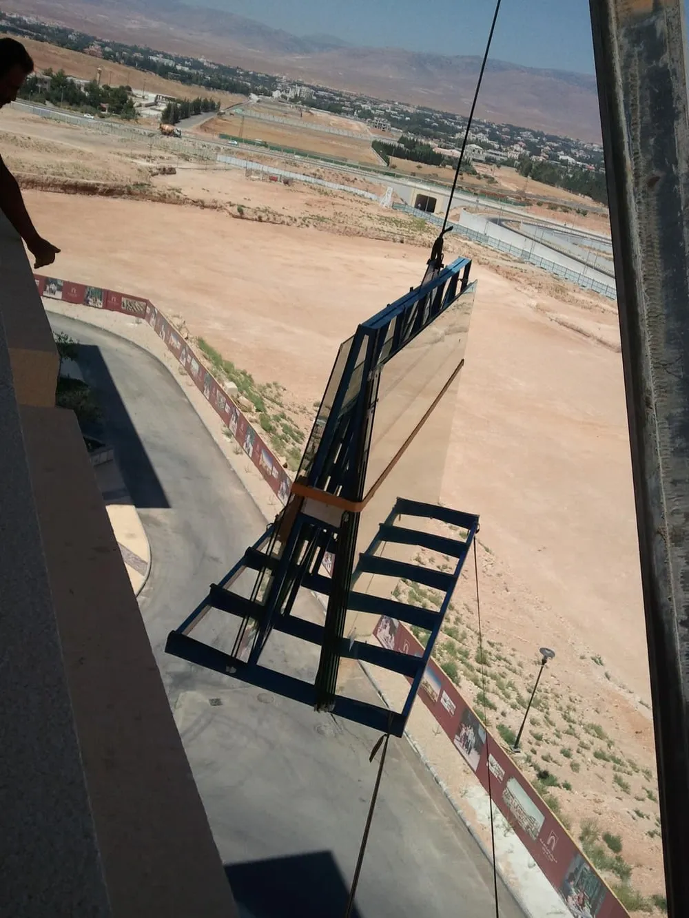 A glazing unit lifted to the facade on a crane frame